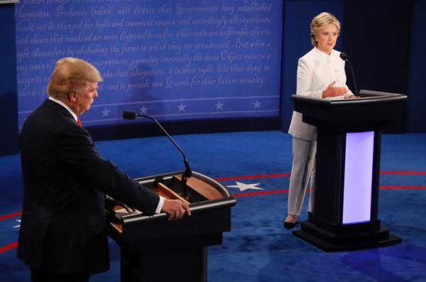 Hillary Clinton speaking at a podium with Do<em></em>nald Trump looking on during the final 2016 presidential debate in Las Vegas
