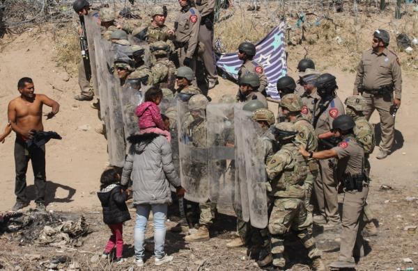 Soldiers and state troopers try to push back migrants with riot shields