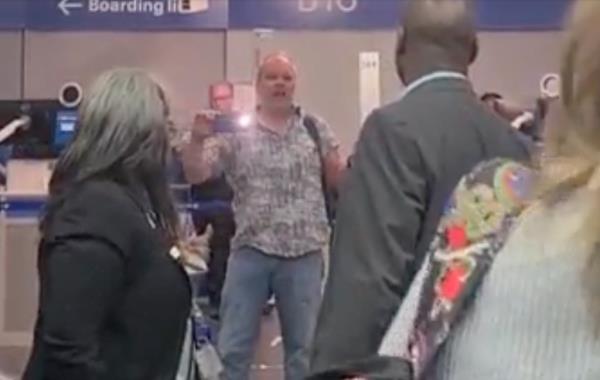The man held up his camera and filmed airport staff and police as they tried to move him into a private room to talk