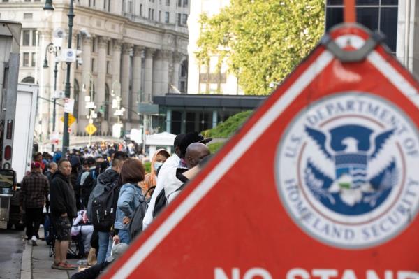 Migrants wait on a sidewalk outside 26 Federal Plaza 