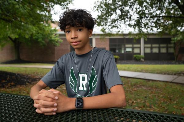 A photo of Caleb Morris, clasping his hands, ouside Ridge High School in Basking Ridge, NJ.