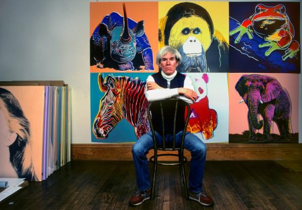 Andy Warhol sits in front of several paintings in his 'Endangered Species' at his studio, the Factory, in Unio<em></em>n Square, New York, New York, April 12, 1983.