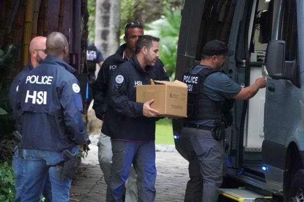 Law enforcement officers carrying boxes of evidence and a laptop from Diddy's mansion during a federal sex trafficking investigation raid