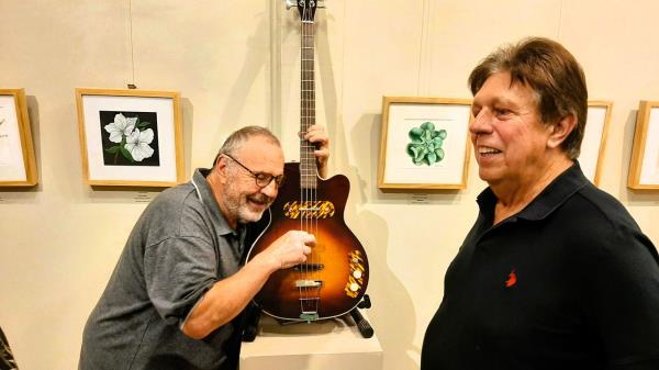 Bassist Mark Pfaff, left, and guitarist Warren Wolf couldn't keep their hands off the exhibits at a recent book launch party for Roger Fritz, subject of the new book 