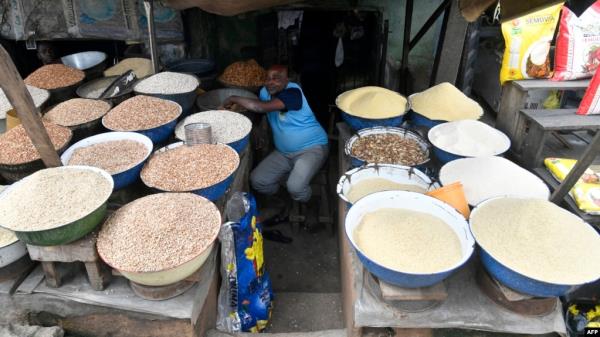 FILE - A vendor sits at his food stall waiting for buyers at a Lagos food market on July 25, 2023. Millions of people in Nigeria are struggling with eco<em></em>nomic problems analysts say were caused in part by government reforms introduced earlier this year. 