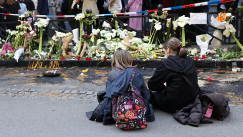 EPA Girls sit on the pavement as people cue to sign the book of co<em></em>ndolence for the victims of a shooting in front of the Vladislav Ribnikar elementary school in Belgrade, Serbia