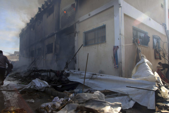 Palestinians try to extinguish a fire at a building of an UNRWA vocatio<em></em>nal training centre which displaced people use as a shelter, after being targeted by Israeli tank shill in Khan Younis.