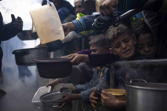 Palestinians line up for food in Rafah, Gaza Strip. Some Gazans attempting to flee, including to Australia, as internatio<em></em>nal aid agencies say the territory is suffering from shortages of food, medicine and basic supplies.